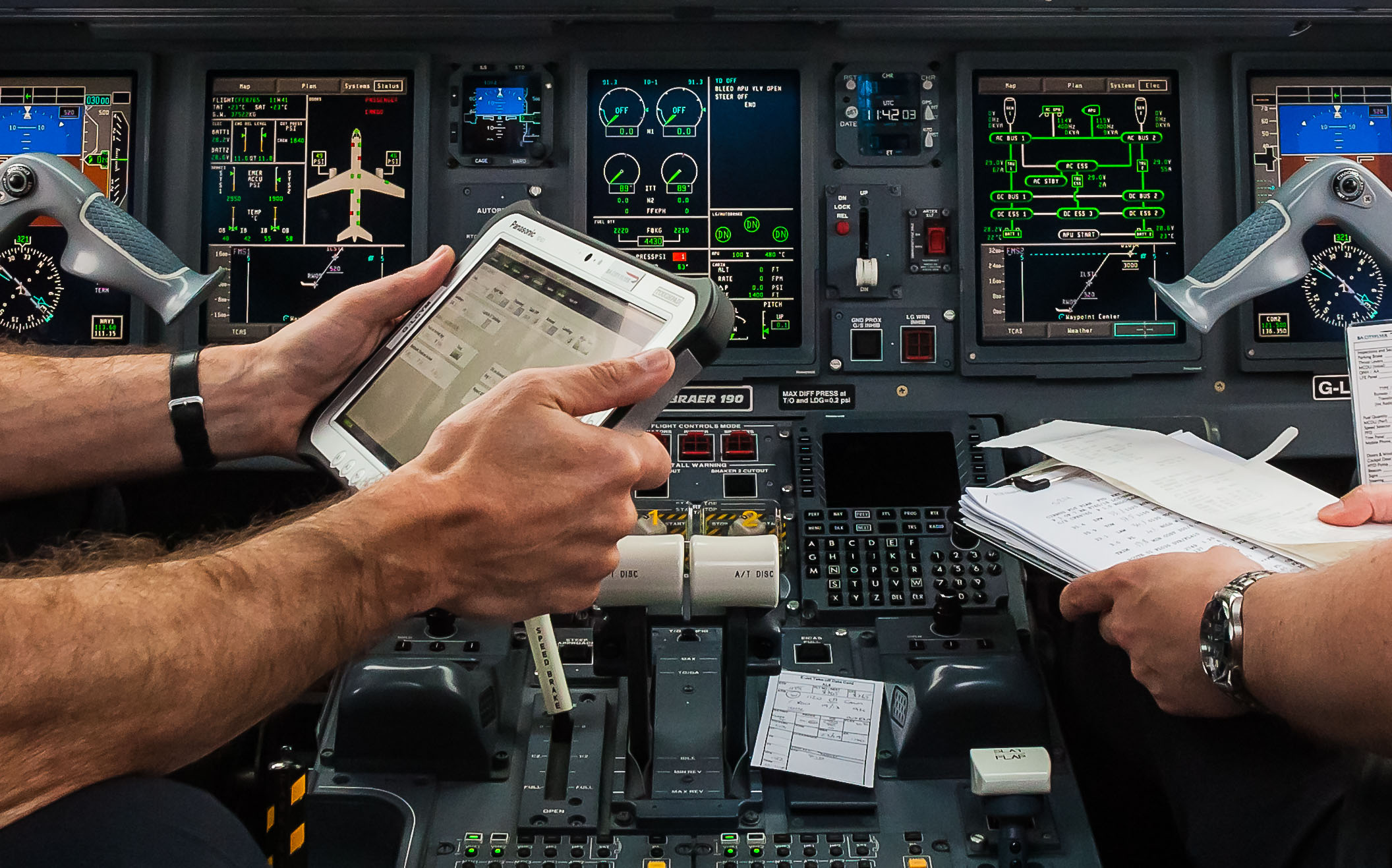 Flight-deck crew using a handheld electronic technical log beside paper documents