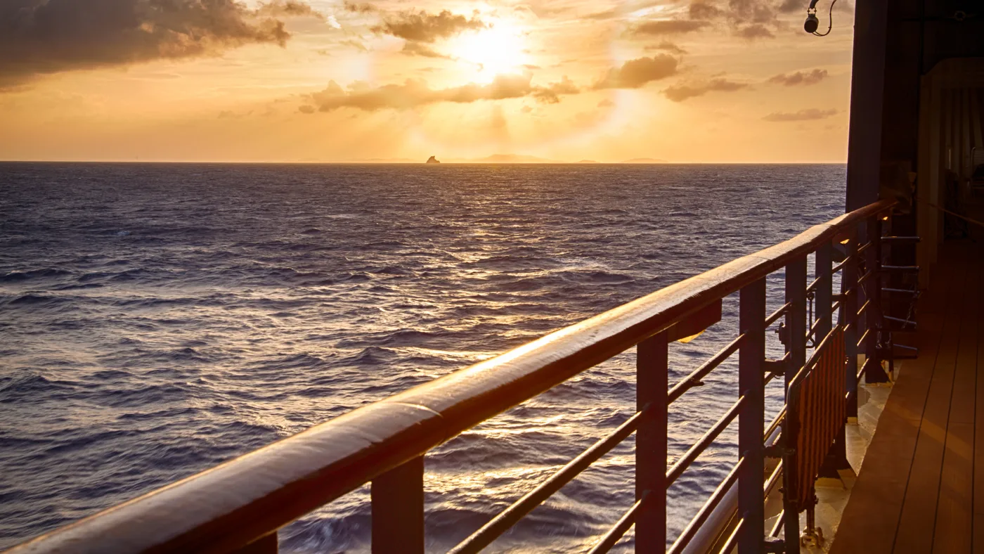 View from a vessel deck across the sea at sunset